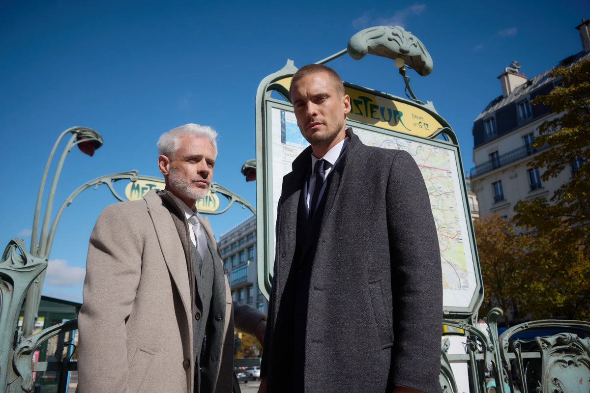 Dos hombres con abrigos beis y gris junto a una boca de metro de París, lookbook de Jerem